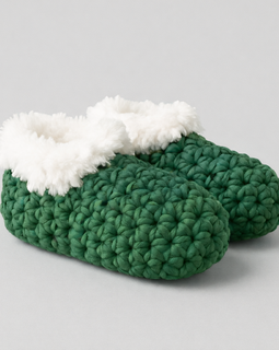 Green crochet slippers with white fur lining on a gray background