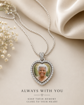 Heart-shaped photo pendant necklace on a beige fabric background with text 'Always with you, keep their memory close to your heart'.