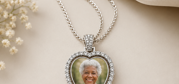 Heart-shaped photo pendant necklace on a beige fabric background with text 'Always with you, keep their memory close to your heart'.