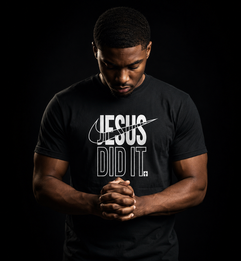 A man wearing a black t-shirt with a white graphic that reads 'JESUS DID IT.' against a solid black background.